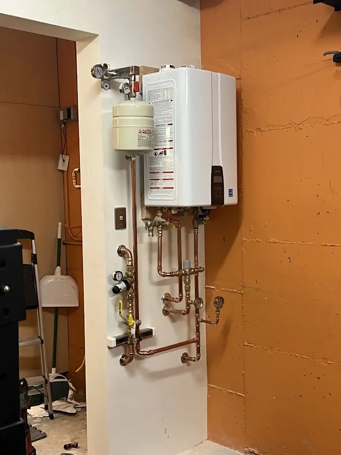 Plumbing technician inspecting water heater connections in East Rockingham